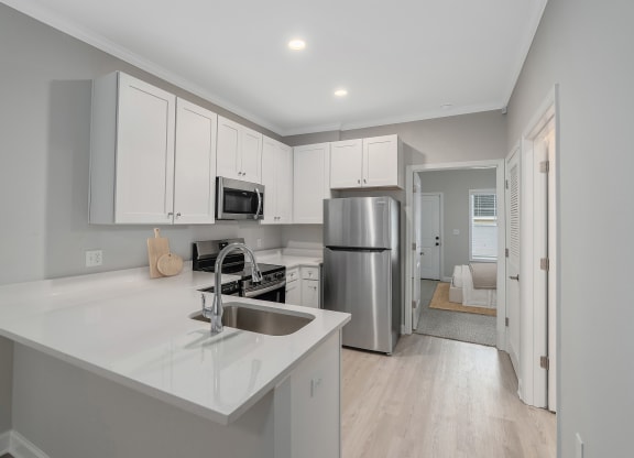 a kitchen with white cabinets and a stainless steel refrigerator at The Cottages at Foley Farms apartments in Foley, AL