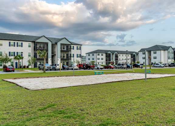 a grassy area with several apartment buildings in the background