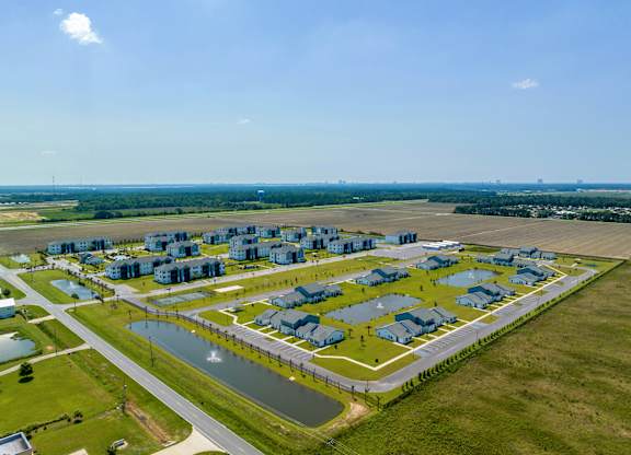 an aerial view of a housing complex in a grassy area next to a body of water