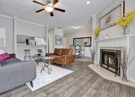 A living room with wood-style flooring, ceiling fan, and fireplace at Village at Caldwell Mill in Birmingham, AL