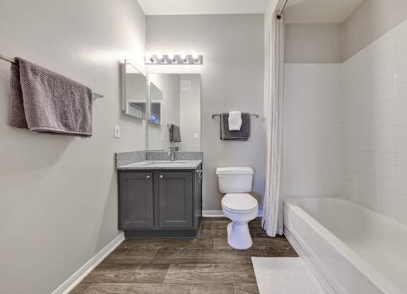 bathroom with wood-style flooring and white bathtub/shower combo at Village at Caldwell apartments in Birmingham, AL