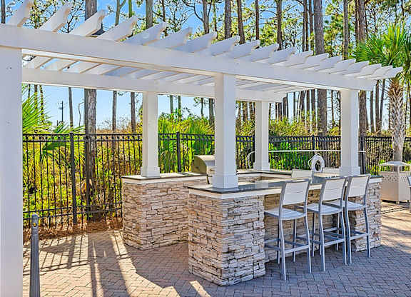A patio with a white pergola and a stone pillar.