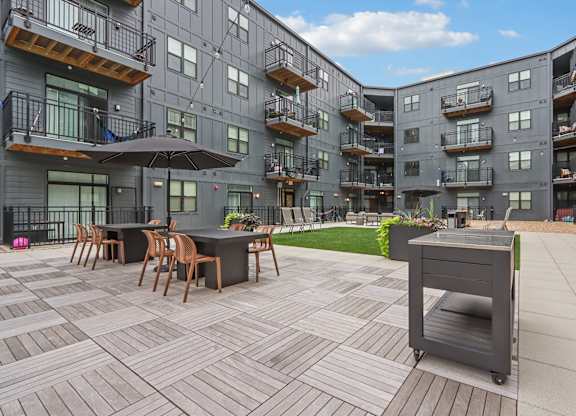 A patio with a table and chairs is surrounded by apartment buildings.