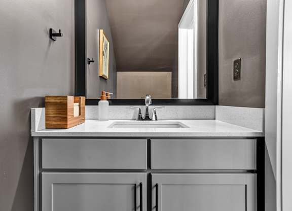 A modern bathroom with a undermount sink, framed mirror, and quartz countertops at West Row Lofts and Townhomes in Birmingham, AL.