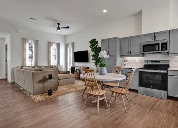 A modern kitchen and living room with wood-designed flooring at West Row Townhomes and at West Row Townhomes at West Row Lofts and Townhomes in Birmingham, AL