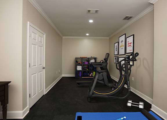 A room with a treadmill, exercise bike, and weights.