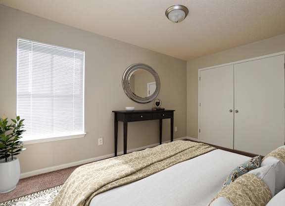 A bedroom with a bed, desk, and mirror.