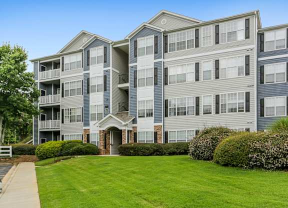 A large apartment building with a green lawn in front.