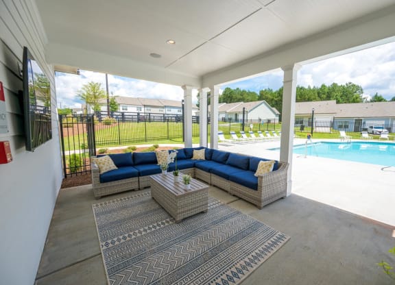 a covered patio with couches and a table next to a pool