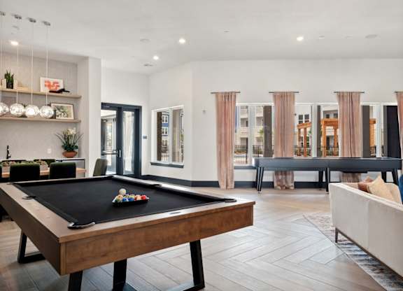 A pool table is in the middle of a living room.