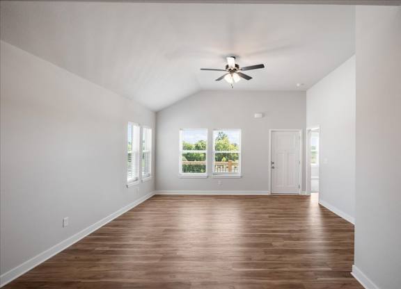 A room with a ceiling fan and wooden flooring.