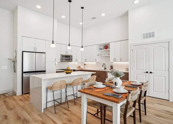 A modern kitchen with a dining table set for four.
