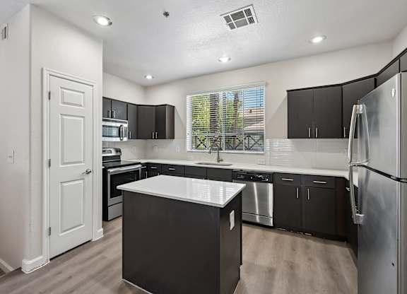 A modern kitchen with black cabinets and stainless steel appliances.