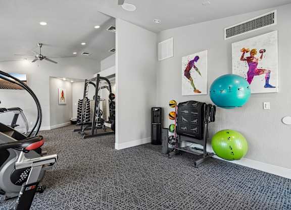 A gym with a row of exercise bikes and a wall with exercise pictures.
