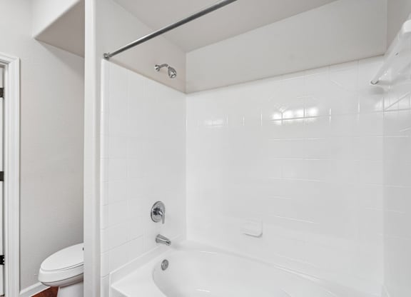 A white bathroom with a toilet and a bathtub.