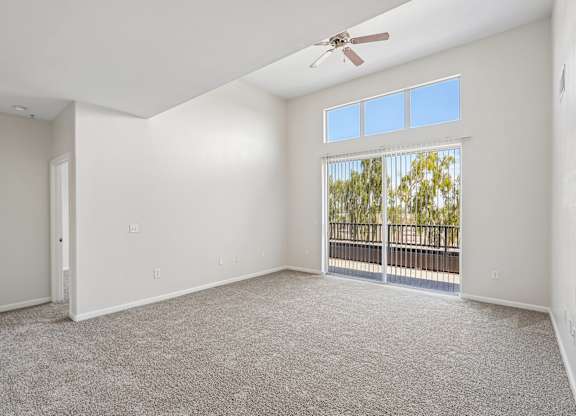 A spacious room with a ceiling fan and a view of trees through the window.