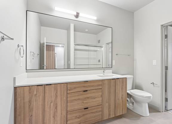 A bathroom with a white countertop and wooden cabinets.