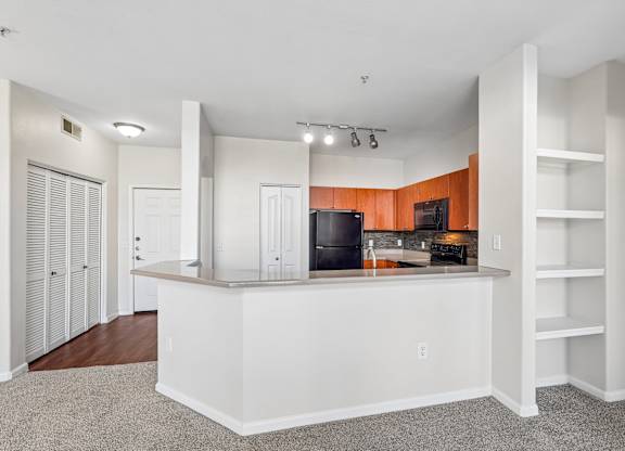 A kitchen with a white counter and a TV on the wall.