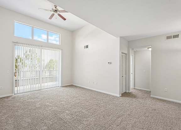 A room with a ceiling fan and carpeted floor.
