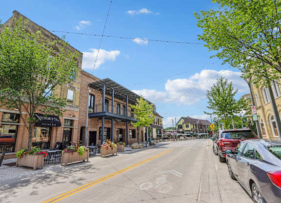 A street view with cars parked on the side and a building with a sign that reads