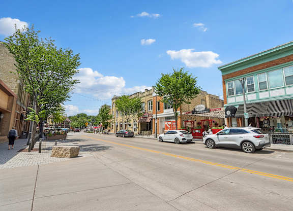 A street view of a town with cars parked on the side of the road.