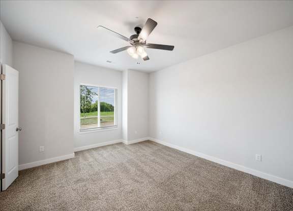 A room with a ceiling fan and carpeted floor.