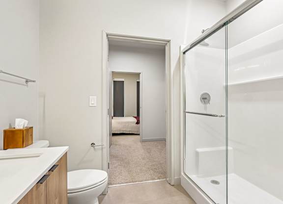 A white bathroom with a toilet, sink, and shower.