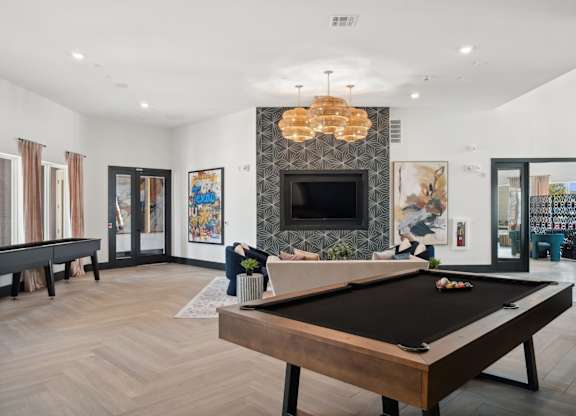 A pool table is in the middle of a room with a fireplace and a chandelier.