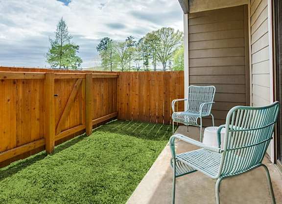 a patio with two chairs and a fence