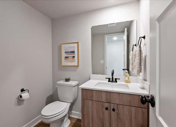 A bathroom with a toilet, sink, and a mirror.