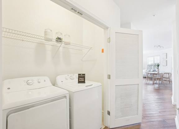 A white washing machine and dryer are in a small laundry room.