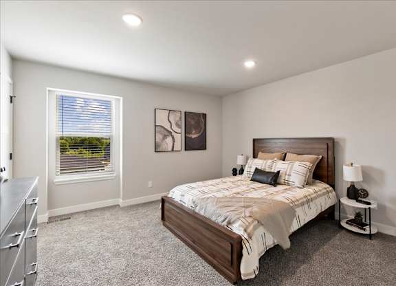 A bedroom with a large bed and a window with blinds.