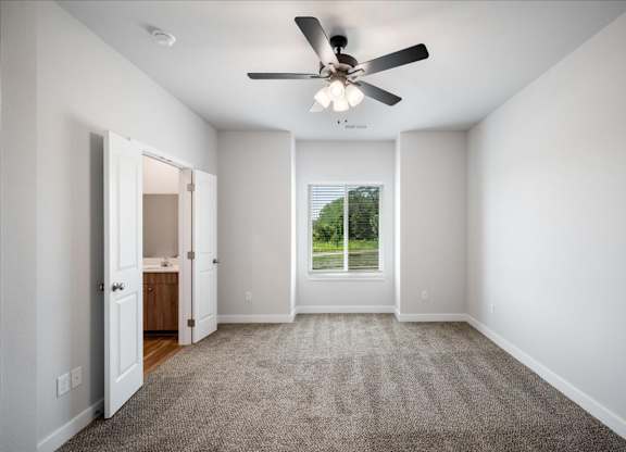 A room with a ceiling fan and carpeted floor.
