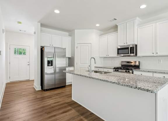 A kitchen with white cabinets and a granite countertop.