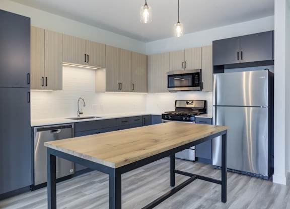 A modern kitchen with a wooden table and stainless steel appliances.