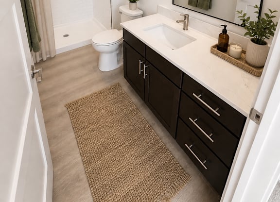 A bathroom with a white toilet, sink, and a brown rug.