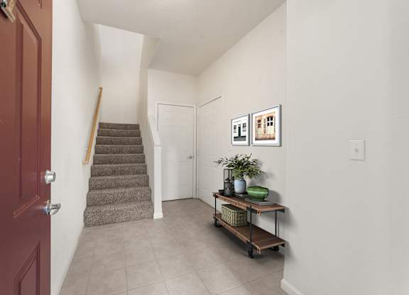 A hallway with a staircase and a table with a plant on it.