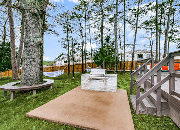 a patio with a grill and a tree