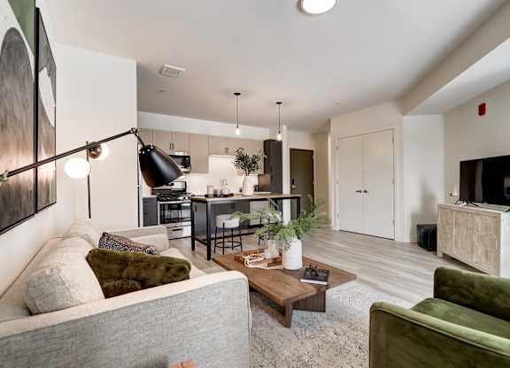 A modern living room with a grey couch and a green armchair.
