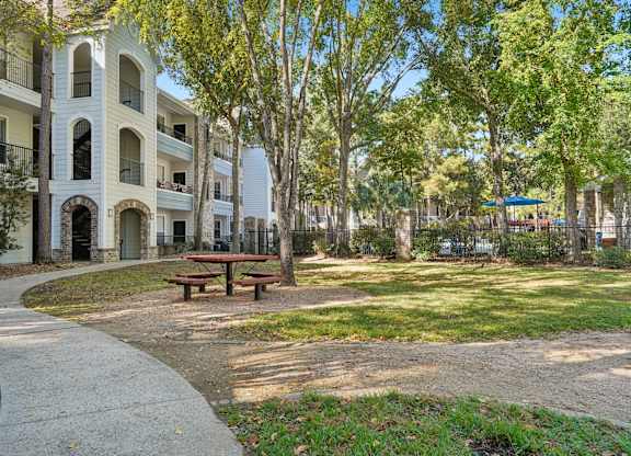 A park with a picnic table and apartment buildings in the background.