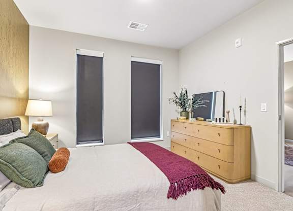 A bedroom with a bed, nightstand, and a dresser with a mirror.