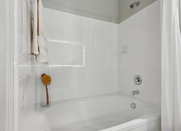 A white bathroom with a white tub and a white shower curtain.