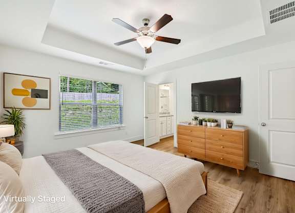 A bedroom with a bed, dresser, and ceiling fan.