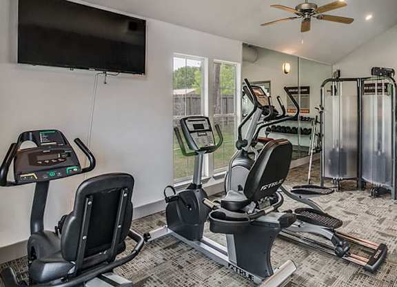 a gym with various exercise machines and a tv