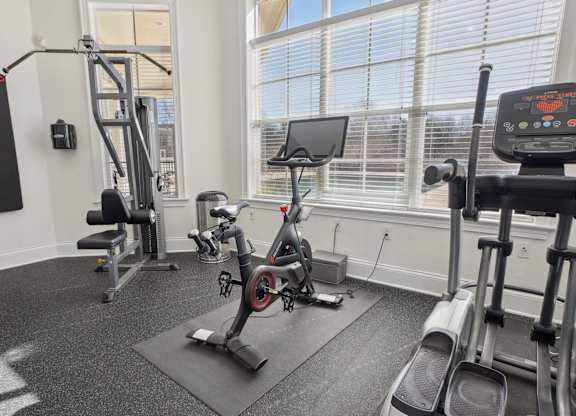 A gym with a variety of equipment including a treadmill, weights, and a bench press.