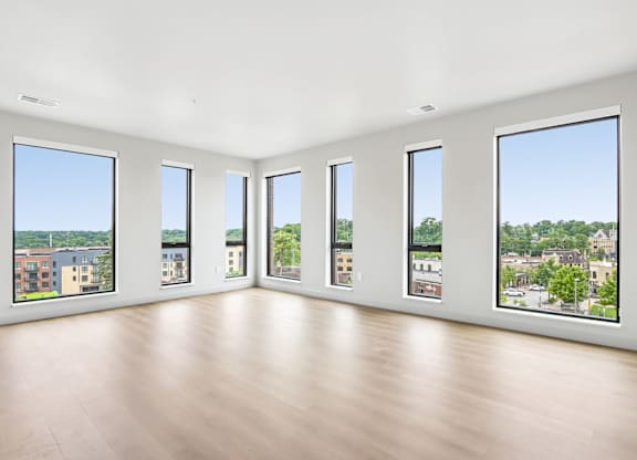 A large empty room with wooden floors and windows overlooking a cityscape.
