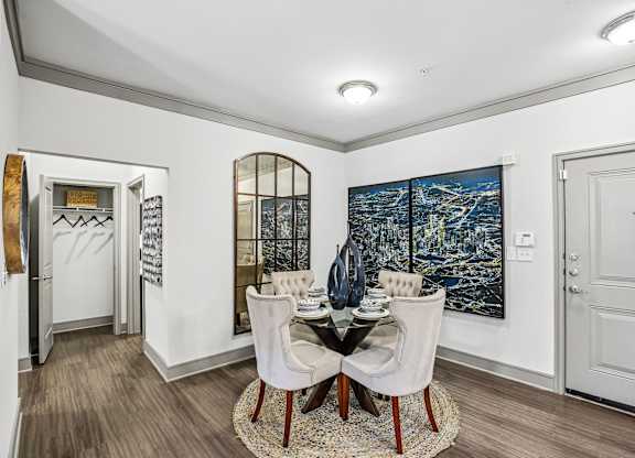 A dining room with a table set for two and a large painting on the wall.