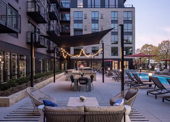 a patio with tables and chairs and a pool at dusk