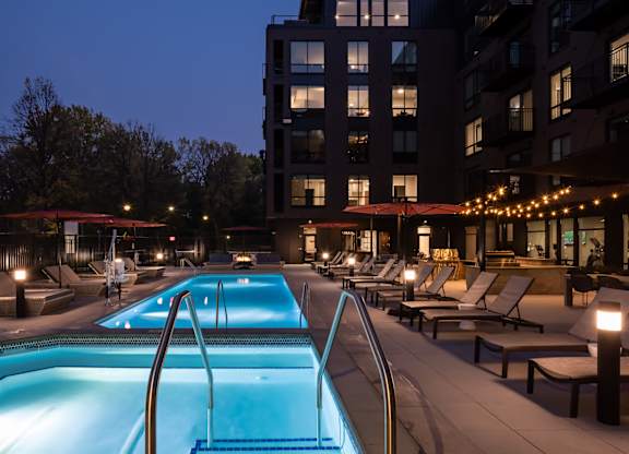 a swimming pool at night in front of an apartment building