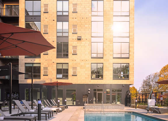 a swimming pool with blue lounge chairs in front of a building